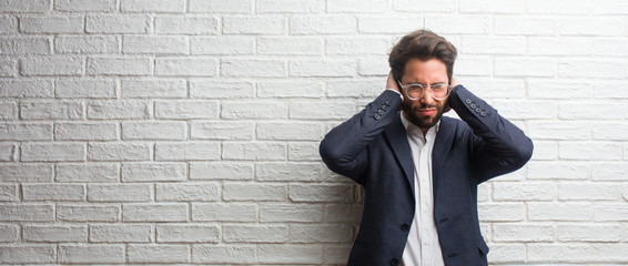 Young friendly business man covering ears with hands, angry and tired of hearing some sound