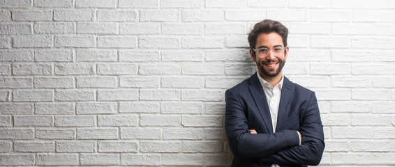 Young friendly business man crossing his arms, smiling and happy, being confident and friendly