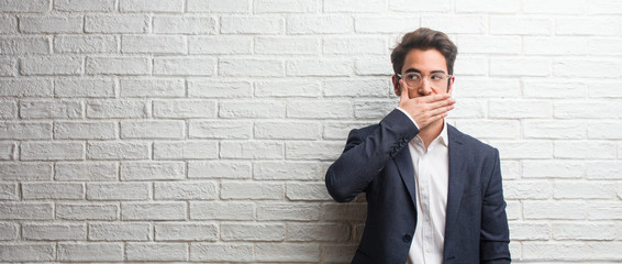 Young friendly business man covering mouth, symbol of silence and repression, trying not to say...