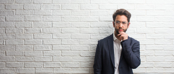 Young friendly business man doubting and confused, thinking of an idea or worried about something