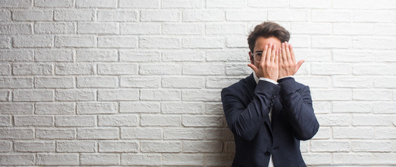 Young friendly business man looking through a gap, hiding and squinting