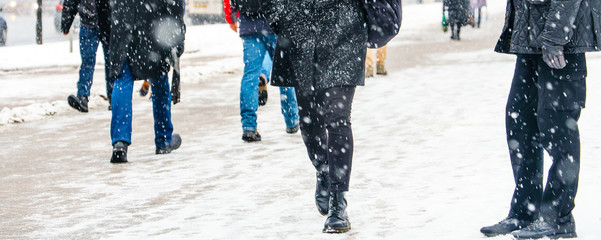 Winter City Slippery Sidewalk. Back view on the feet of people walking along the icy snowy pavement. Pair of shoe on icy road in winter. Abstract empty blank winter weather background