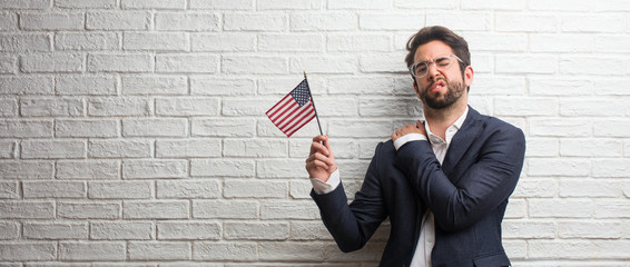 Young business man wearing a suit against a white bricks wall with back pain due to work stress,...
