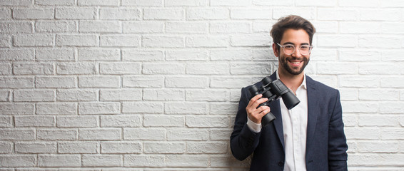 Young business man wearing a suit against a white bricks wall cheerful and with a big smile, confident, friendly and sincere, expressing positivity and success