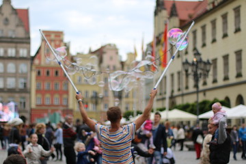 Man blowing beautiful, soap bubbles. Warm, pleasant, spring day. Family atmosphere in the outdoors. Active rest, weekend in the city. Relaxing people. Great fun outside. Variety of colors. Freedom.