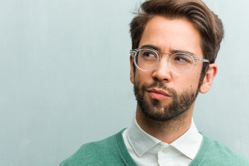Obraz premium Young handsome entrepreneur man face closeup doubting and confused, thinking of an idea or worried about something