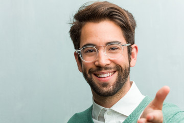 Young handsome entrepreneur man face closeup reaching out to greet someone or gesturing to help, happy and excited