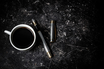 A cup of black coffee with a male fountain pen. Concept fashion business style. 