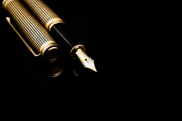 Golden pen on a dark isolated background
