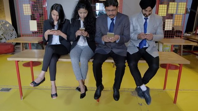Tilt up to colleagues in business formals jus wasting time while being addicted and looking only at their phone screens and ignoring each other, young and old, males and females at a coworking space
