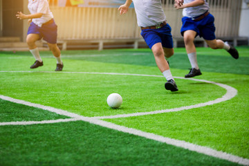 Asian student play plastic soccer ball on green artificial turf