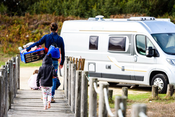 Family walking to camper van with box of toys.