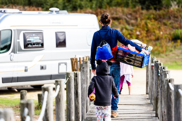 Family walking to camper van with box of toys.