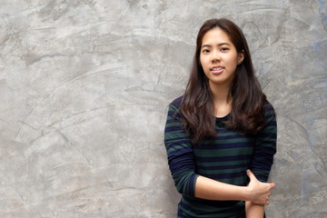 Young pretty asian woman smiling in grey concrete wall background.