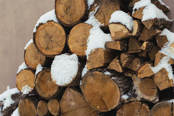Chopped stock of firewood under snow on the street. Firewood for fireplace and bbq
