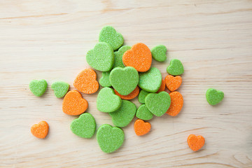 Colorful candy hearts orange and green on wooden background Top