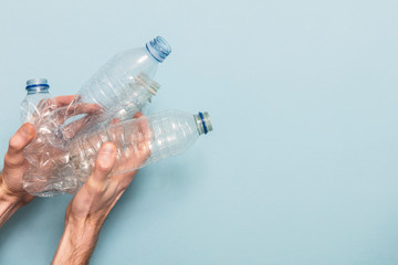 Hand holding empty plastic bottle recycling against a blue background
