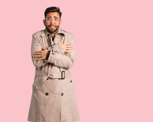 Young man wearing trench coat going cold due to low temperature
