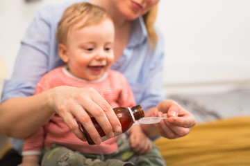 mother giving cough syrup to her son