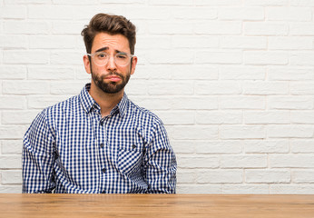 Young caucasian man sitting worried and overwhelmed, forgetful, realize something, expression of shock at having made a mistake