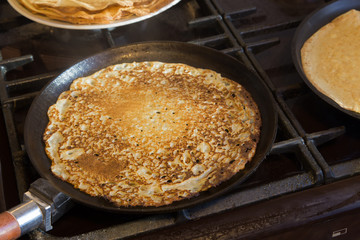 Traditional russian blini on a cast-iron frying pan.