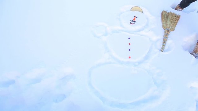 A girl in the snow drew a snowman and put a lid on his head