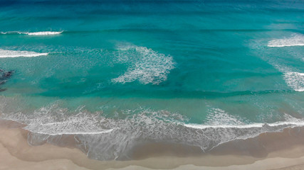 Aerial view of beautiful waves along the seashore on a sunny day, holiday and travel concept
