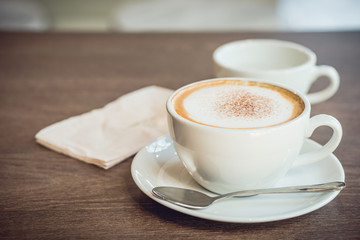 Hot coffee and hot tea place on the wooden table in early morning with copyspace, white cup and silver spoon.