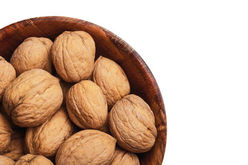 Walnuts in wooden bowl isolated on white studio background. Whole nuts in shells in round container with empty copy space for graphic design text.