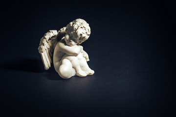 White angel figurine with heart on black background, Valentine's Day.