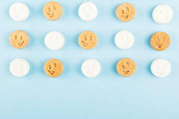 White and brown sugar smiles on blue background. Top view, copy space. Food background