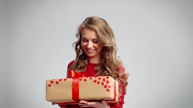 Excited woman opening a gift in studio shot