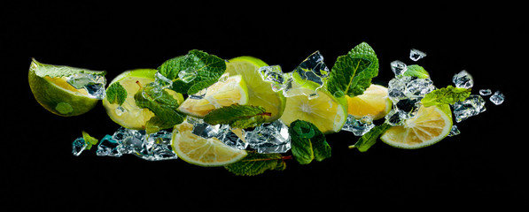 Lime pieces with leaves of peppermint on black background.