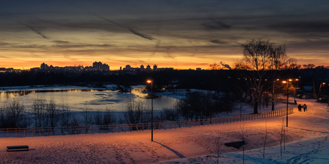 Fototapeta na wymiar winter evening cityscape. view of the residential area across the river in the background of the sunset