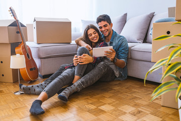 Young couple moving in new home.Sitting on floor and relaxing after cleaning and unpacking.