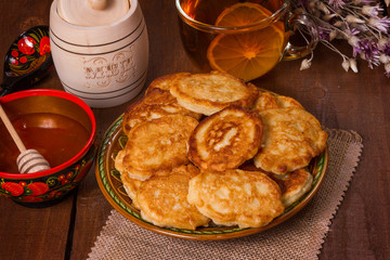 curd fritterspancakes with honey on a wooden table tea with lemon