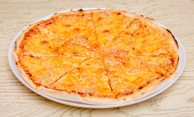 Pizza on a round white plate in a restaurant on a wooden table_