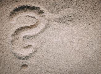 Fototapeta na wymiar Question mark written with the finger in sand