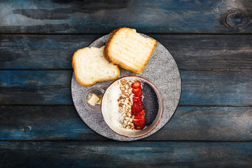 Healthy breakfast. Rice cereal or porridge with fresh strawberry, almond and coconut flakes, served with bread and butter. On a beautiful wooden background, top view