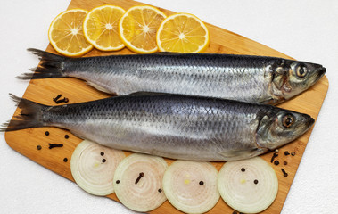 Herring on a cutting board with onions and lemon