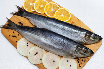 Herring on a cutting board with onions and lemon