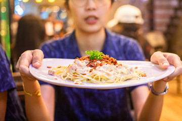 Woman holding a plate of spaghetti 