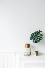 Artificial plant in glass vase with gold stainless trim edge and gold mirror vase setting on empty  fireplace in minimal modern style / cozy interior concept / empty space fo advrtisement