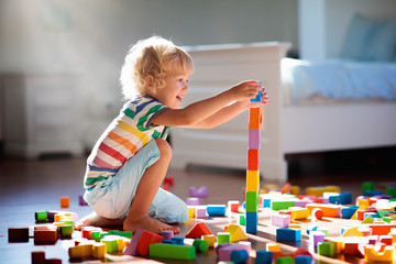 Child playing with colorful toy blocks. Kids play. - Powered by Adobe