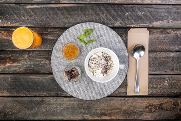 Healthy breakfast bowl with banana and apple with apple jam dates and fresh juice. On a beautiful wooden background, top view