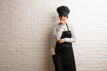 Young baker indian woman against a bricks wall biting nails, nervous and very anxious and scared for the future, feels panic and stress