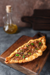 Turkish handmade pide lies on an blue surface. Cherry tomatoes, parsley, lemon, hot pepper, garlic are on the table.