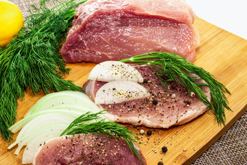 meat steak on a board with onion greens and lemon