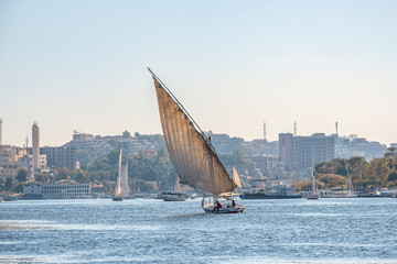 12.11.2018 Aswan, Egypt, A boat felucca sailing along a river of nilies on a sunny day against a city background