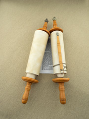 A scroll of the Torah on wooden bonds, a pointer, a rough canvas.